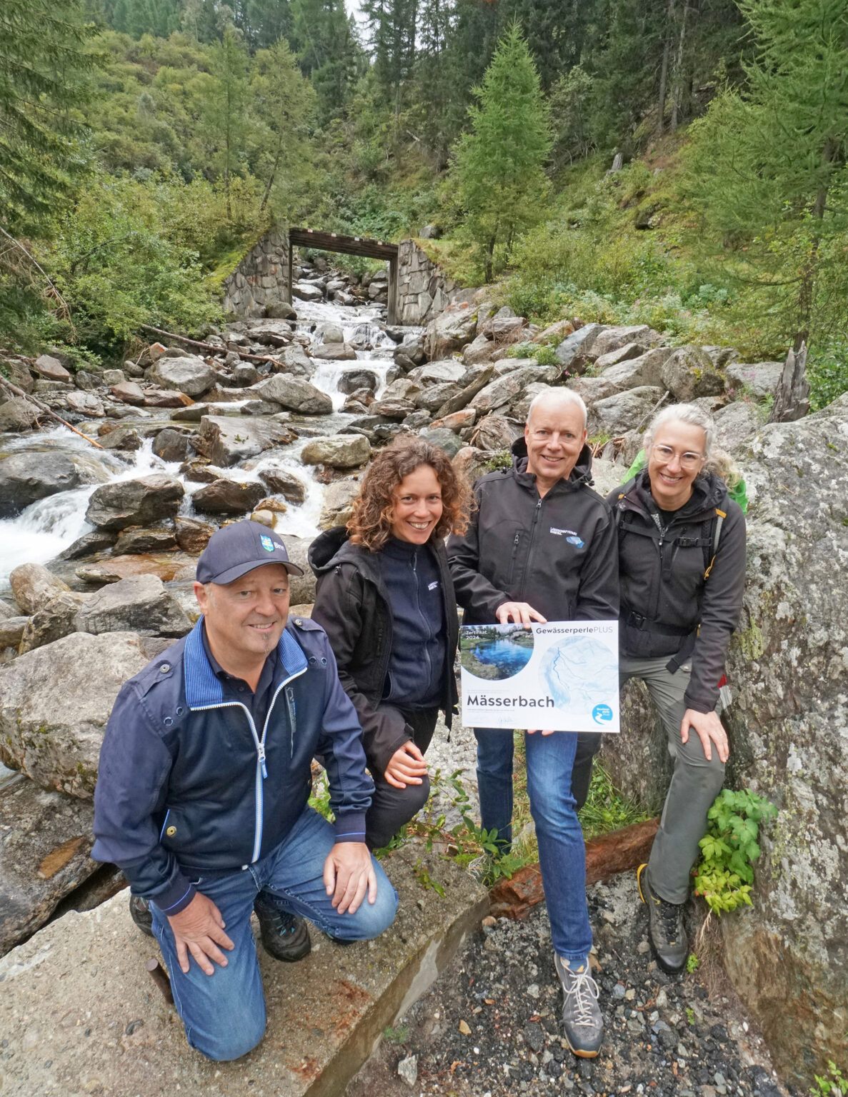Übergabe des Labels «Gewässerperle PLUS». Von links nach rechts: Rudolf Jossen, Gemeindepräsident von Binn, Barbara Grendelmeier, Projektleiterin Landschaftspark Binntal, Francesco Walter, Vizepräsident Landschaftspark Binntal, Antonia Eisenhut, Verein Gewässerperlen. Foto: Brigitte Wolf (zvg)