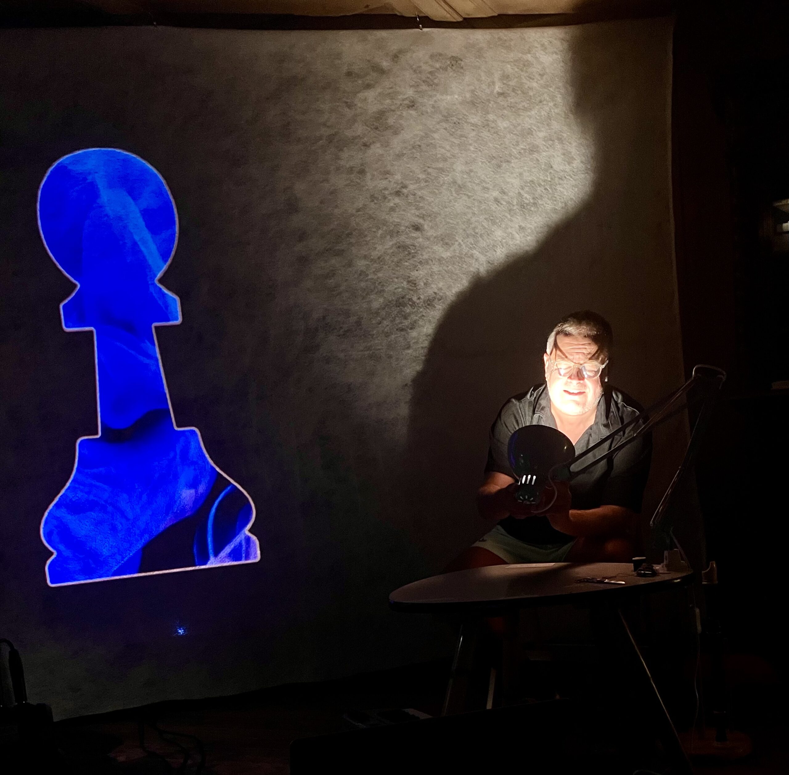 Die Bauernfigur als Symbol für Woyzeck: Eine blaue Projektion trifft auf die Schatten der Tischlampe – das Wohnzimmer wird zur Bühne.