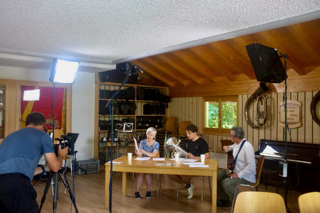 Auf einer musikalischen Reise durch die Schweiz trifft Roman Walker (rechts) die Sängerin Sophie Jaccard und den Euphonium-Spieler Benoît Zufferey. Die Aufnahmen fanden im Probelokal des Echo des Alpes in Vissoie statt. Links im Bild Kameramann Reto Indergand. (Foto: Mesch & Ugge AG, Zürich) 