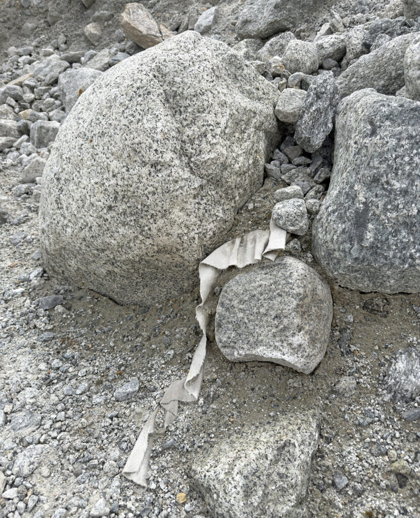 Ein Stück der verwitterten Abdeckung liegt zwischen Geröll und Sand im Gletschervorfeld. Solche Kunststoffreste nähren die Kritik am Betrieb der Eisgrotte. Aufnahme vom 4. Juni 2026. © Brigitte Wolf